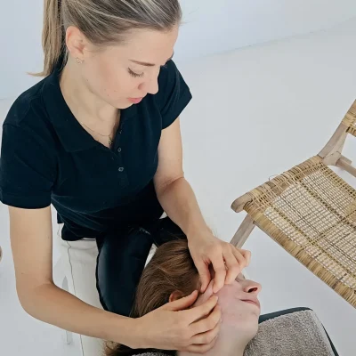 Fizjoterapeutka stomatologiczna przeprowadza sesję fizjoterapii z pacjentką.